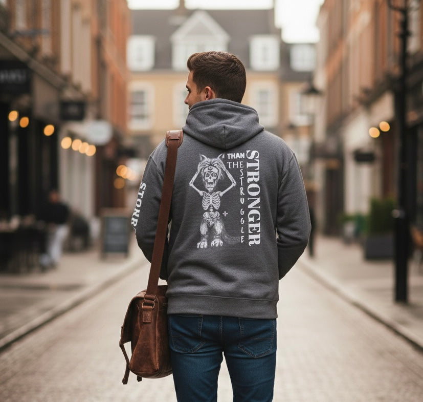 Man wearing a hoodie with a design and text on the back, walking down a street.