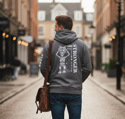 Man wearing a hoodie with a design and text on the back, walking down a street.